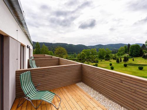 a balcony with two chairs and a view of a field at Cihelny Golf & Wellness Resort in Karlovy Vary
