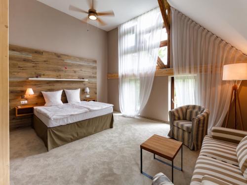 a bedroom with a bed and a couch and a chair at Cihelny Golf & Wellness Resort in Karlovy Vary