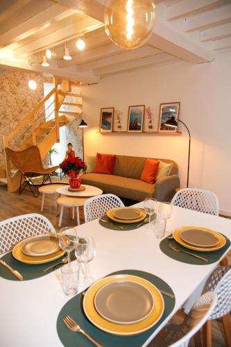 une salle à manger avec une table, des chaises et un canapé dans l'établissement Normandy Sérénity Cottage, à Grandcamp-Maisy