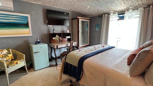 a bedroom with a bed and a desk and a television at Villa Lulu Geribá in Búzios