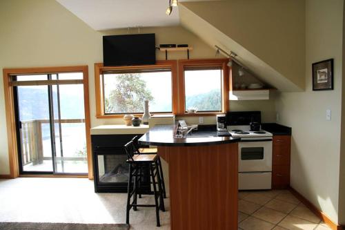 a kitchen with a counter and two windows at Moon Water Lodge in Malahat