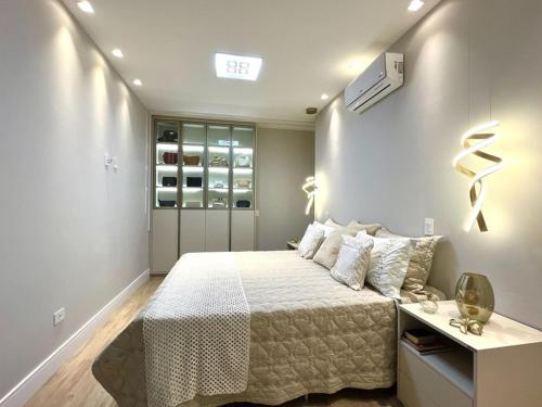 a white bedroom with a bed and a desk at Casa para fins de semana in Maringá