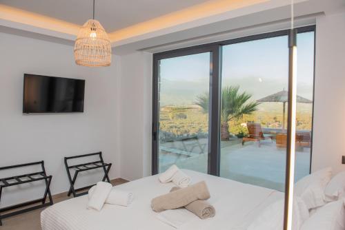 a bedroom with a white bed and a large window at Niki Cretan Villas in Sívas