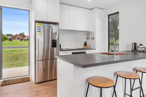 a kitchen with a stainless steel refrigerator and stools at Lakeside Treasure - Mangakino Holiday Home in Mangakino