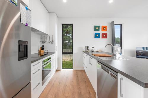 a kitchen with white cabinets and a wooden floor at Lakeside Treasure - Mangakino Holiday Home in Mangakino