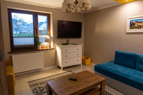 a living room with a blue couch and a tv at GOLD apartamenty & spa in Szczawnica