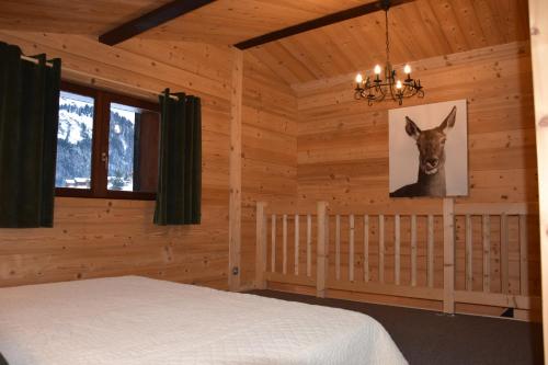 - une chambre avec un lit et une photo de cerf sur le mur dans l'établissement La Coufa, spacieux Duplex en chalet, terrasse, jardin, vues montagnes, à La Giettaz