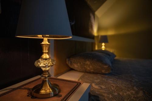 a lamp sitting on a table next to a bed at GOLD apartamenty & spa in Szczawnica