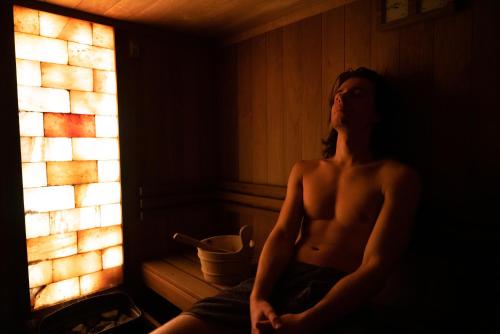 a shirtless man sitting in a room next to a fireplace at GOLD apartamenty & spa in Szczawnica