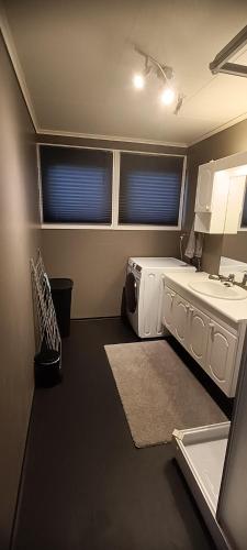 a bathroom with a sink and a washing machine at Gauvik - Lyngdal in Lyngdal