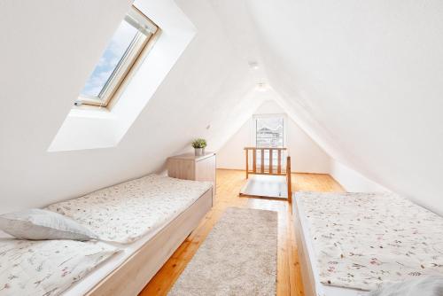 a attic bedroom with two beds and a window at Wellness Apartmány Andrea in Zdíkov