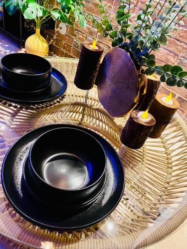 a table with three black plates and candles on it at Saphir Spa - Sauna Balnéo Chromothérapie Massage in Amiens