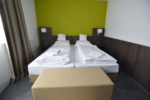2 camas individuales en una habitación con una pared verde en Im Tal 2 Apartment Haus, en Bergheim