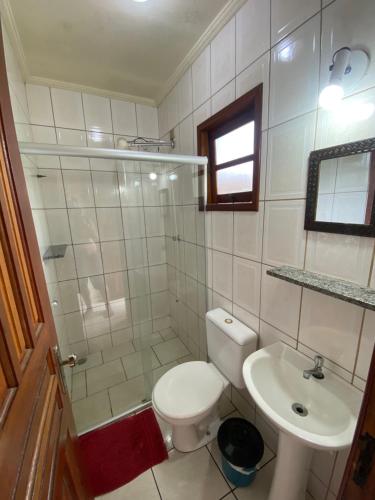 a white bathroom with a toilet and a sink at Pousada Stilo Ponta Negra in Ubatuba