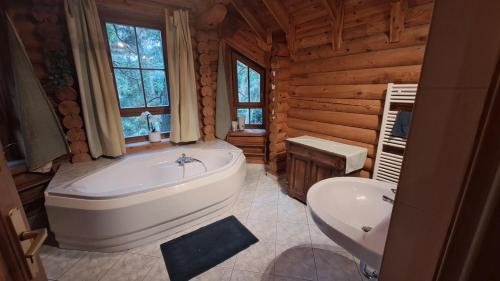 a bathroom with a tub and a sink in a log cabin at Holzhaus am See in Zernsdorf