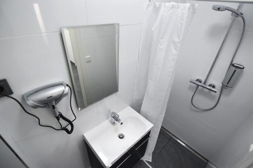 ein weißes Bad mit einem Waschbecken und einer Dusche in der Unterkunft Im Tal 2 Apartment Haus in Bergheim