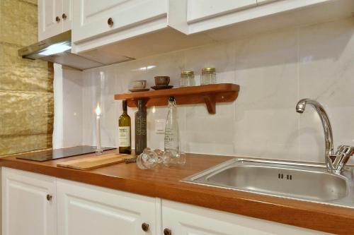 a kitchen counter with a sink and bottles and glasses at Venetian Suite Mitropolis new in Corfu