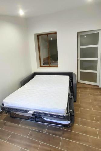 un lit assis dans une pièce avec une fenêtre dans l'établissement Appartement au cœur du village, climatisé avec extérieur, à Gréoux-les-Bains