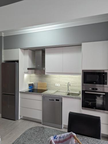 a kitchen with white cabinets and stainless steel appliances at Waterfront 1 Bedroom suite 3 adults PDL in Ponta Delgada