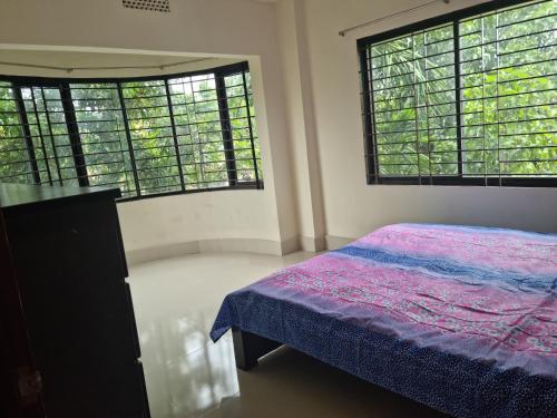 a bedroom with two large windows and a bed at Moshahid Ali House in Sylhet