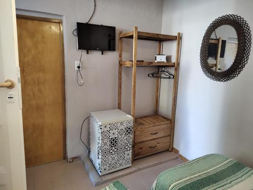 Habitación con TV, estante de madera y espejo. en La Mora Departamento en Mina Clavero