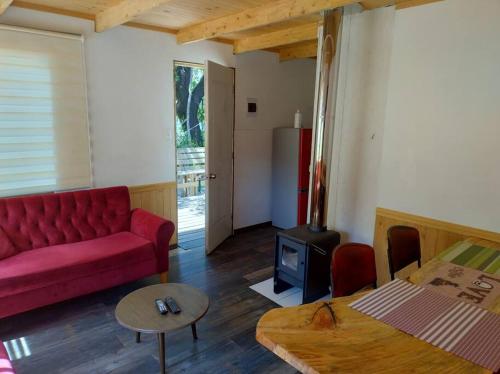 - un salon avec un canapé rouge et une cuisinière dans l'établissement Cabañas Precordillera Radal 7 tazas, à El Torreón