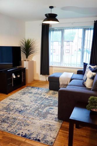a living room with a blue couch and a rug at Villa Retreat Birmingham in Birmingham