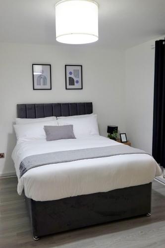 a large bed in a white room with a lamp at Villa Retreat Birmingham in Birmingham