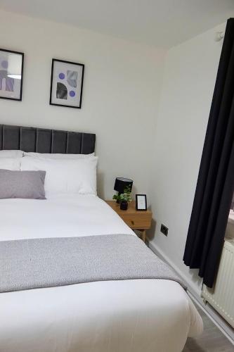 een slaapkamer met een wit bed en een tafel bij Villa Retreat Birmingham in Birmingham