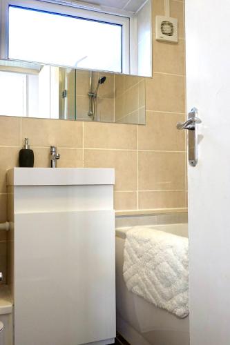 a bathroom with a sink and a tub and a mirror at Villa Retreat Birmingham in Birmingham