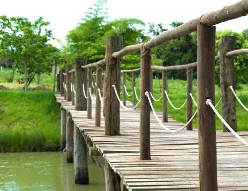 un pont en bois sur une nappe d'eau avec des câbles dans l'établissement Rancho condomínio Terras d barra, 