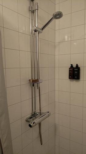 a shower in a white tiled bathroom at Hotel Charlotte / Stella in Uppsala