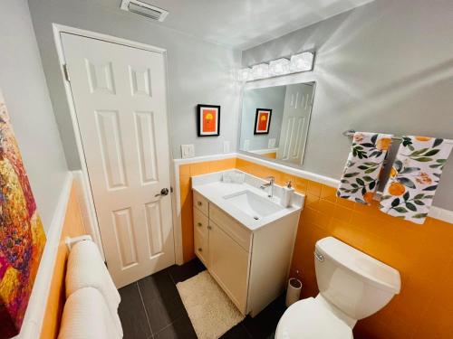 a bathroom with a toilet and a sink and a mirror at Midtown Cottage - In the heart of Cocoa Beach in Cocoa Beach