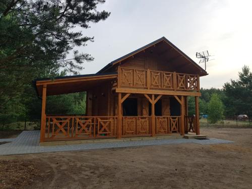 een grote houten hut met een veranda bij Domek na Barcowej in Ostrowo