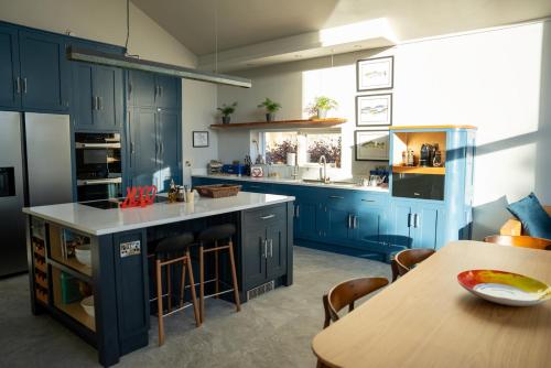 eine Küche mit blauen Schränken und einem Holztisch in der Unterkunft New build eco house in walled garden, Rostrevor in Rostrevor