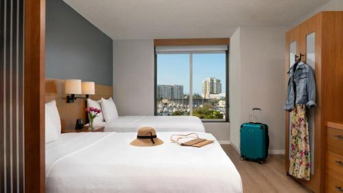 a hotel room with a bed with a hat and a suitcase at Hyatt Place San Juan in San Juan