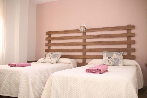 two beds in a room with white sheets and pink pillows at El Rincón de Eli in Rincón de la Victoria