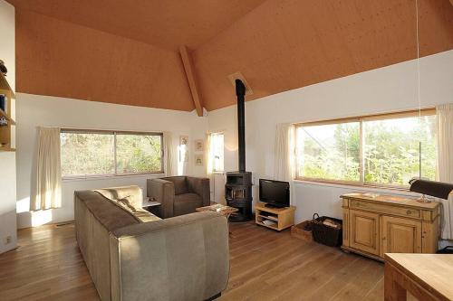 een woonkamer met een bank en een televisie bij Comfortabele woning aan het water, hottub & kachel in Zuidlaren