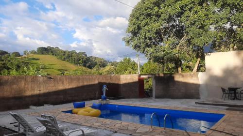 una piscina en un patio con sillas alrededor en chácara Gato de Botas en Socorro