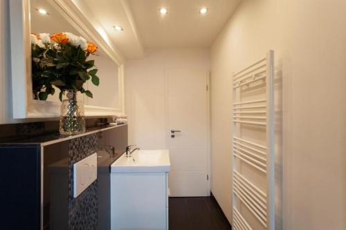 łazienka z umywalką i wazonem kwiatowym w obiekcie City Apart Hannover w Hanowerze