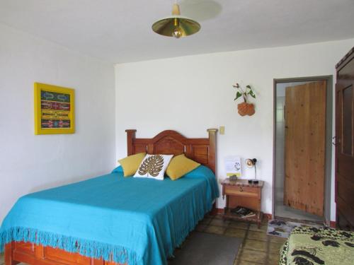 a bedroom with a bed with a blue bedspread at Alojamiento Rural Jardín Consentido in Jardin