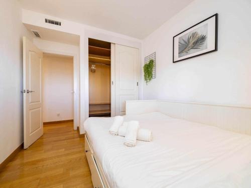 biała sypialnia z białym łóżkiem i ręcznikami w obiekcie Ático con vistas al mar piscina y parking w Maladze