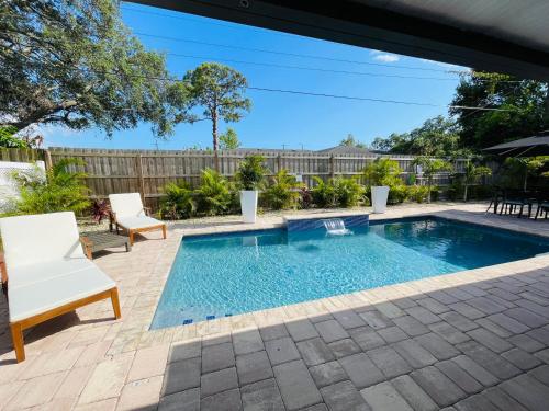 a swimming pool in a yard with two white chairs at Sarasota Paradise home near Siesta Key Beach in Sarasota