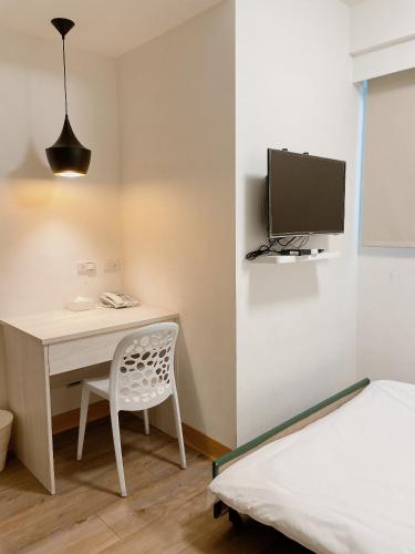 a bedroom with a desk and a bed and a tv at Hotel Huru House in Taichung