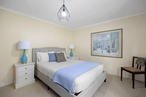 a white bedroom with a bed and a chair at Grand View with Spa & Sauna in Warburton
