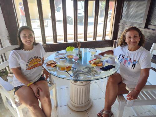 two women sitting at a table with food on it at Pousada L'étage in Búzios