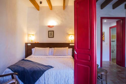una puerta roja que conduce a un dormitorio con cama en Ca la Roseta, en Sant Pere Pescador