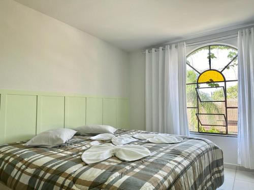 a white bedroom with a bed with pillows and a window at Suíte na casa amarela in Pomerode