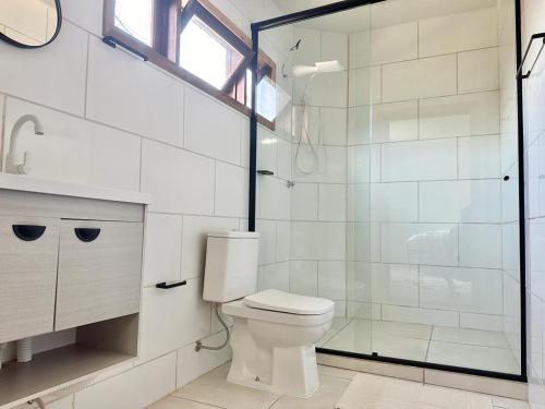 a bathroom with a toilet and a glass shower at Suíte na casa amarela in Pomerode