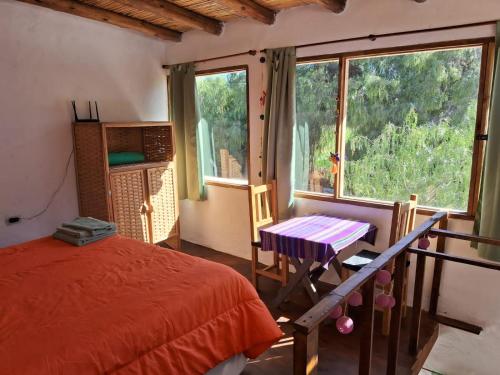 a bedroom with a bed and a table and a window at Cabañas APU in Maimará